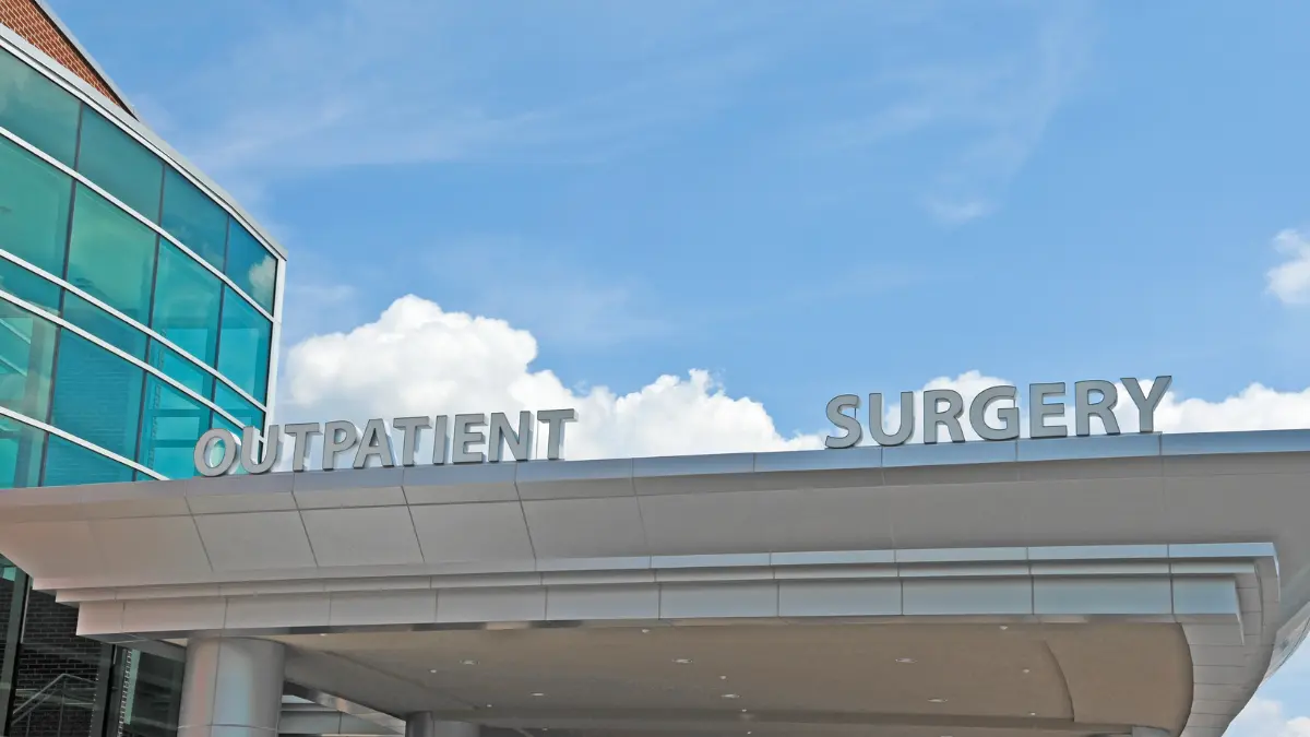 ambulatory-outpatient-surgery-center Exterior entrance of a modern ambulatory surgery center with “Outpatient Surgery” signage beneath a blue sky.