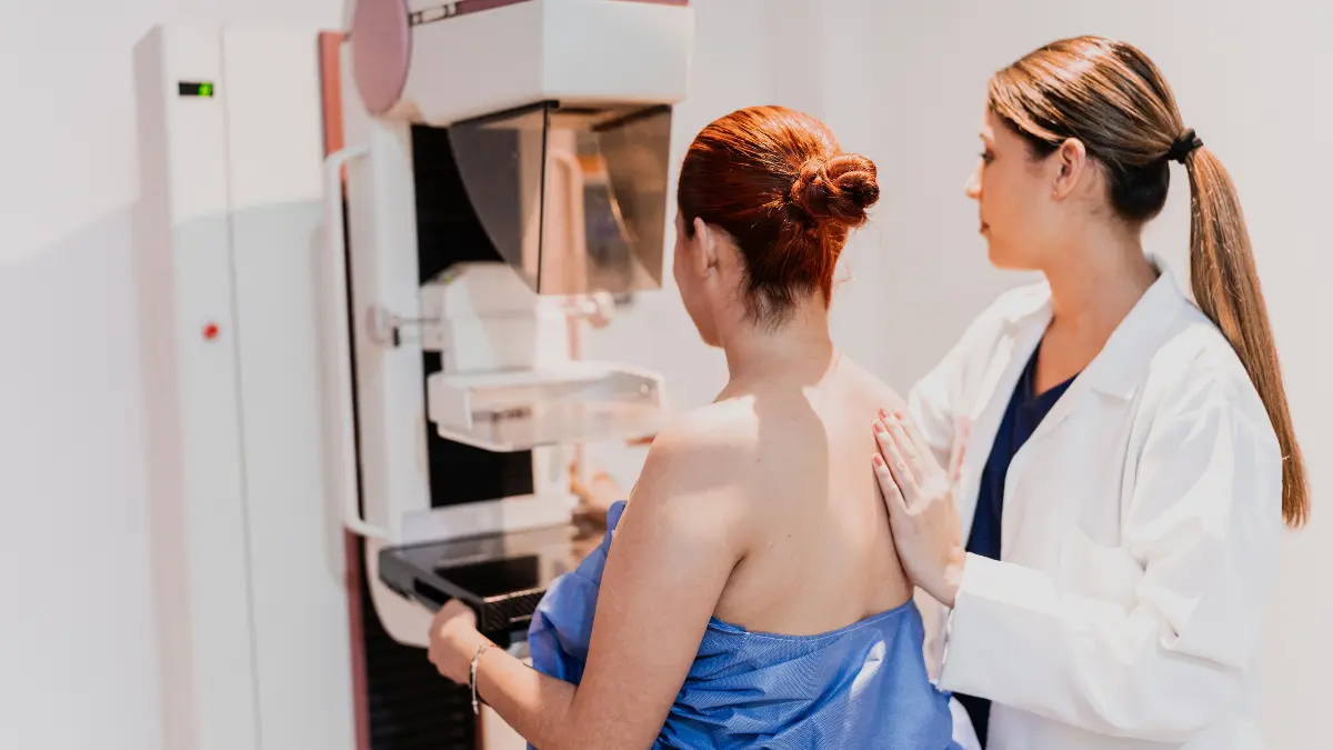 Healthcare professional guiding a woman through a mammogram screening at an imaging center